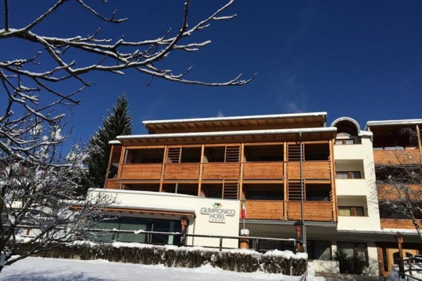 Hotel s dřevěným obložením a zasněženým okolím pod modrou oblohou.