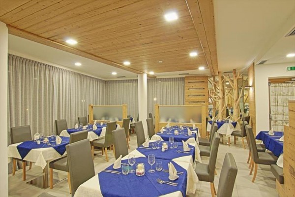 Moderně zařízená restaurace s bílými a modrými ubrusy na stolech.