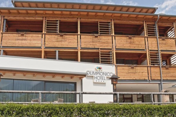 Moderní hotelová budova s dřevěnými balkony a nápisem 