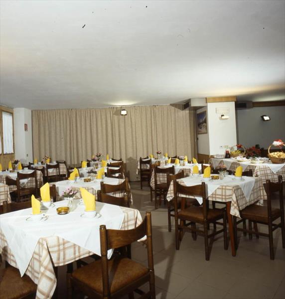 Restaurace s prostřenými stoly, židlemi a žlutými ubrousky.  