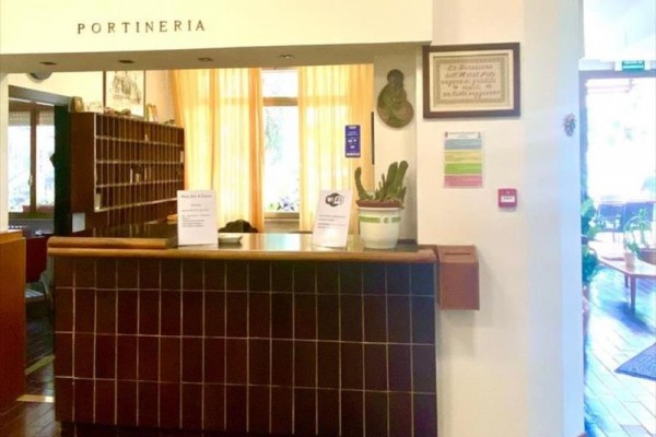 Recepce s pultem a květinou v květináči, nápis 