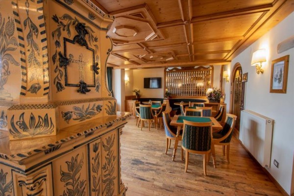 Tradiční interiér restaurace s dřevěným stropem a zdobenou kachlovou pecí.