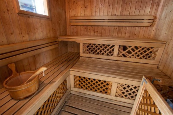 Dřevěná sauna s lavicemi a vědrem na vodu.