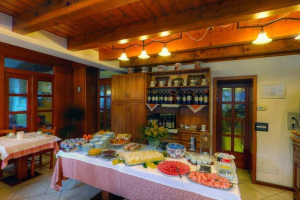 Bohatě prostřený stůl s jídlem a nápoji v restauraci s dřevěným interiérem.  
