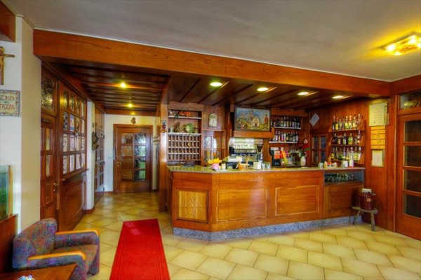 Recepce s dřevěným pultem a regálem s nápoji v interiéru hotelu.