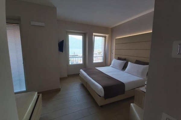 Moderní ložnice s manželskou postelí a velkými okny.