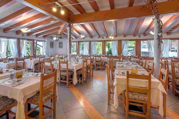 Prostorná restaurace s dřevěným nábytkem a prostřenými stoly.