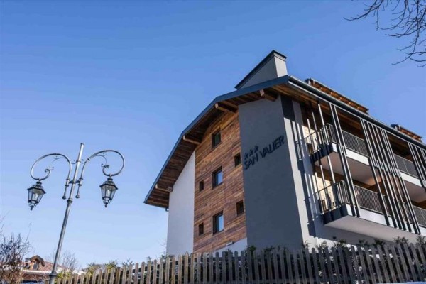 Moderní budova s dřevěnými prvky a balkonem vedle starožitné lampy.