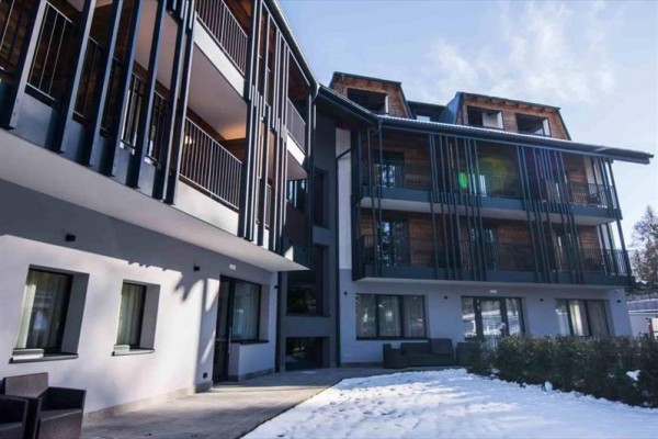 Moderní budova s balkóny a sněhem na zemi.