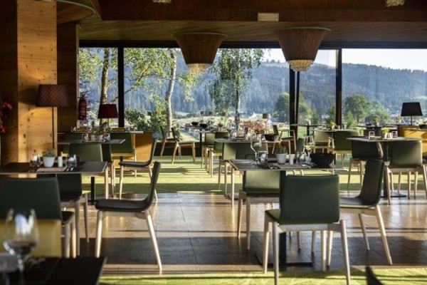 Interiér restaurace s výhledem na lesy a hory.