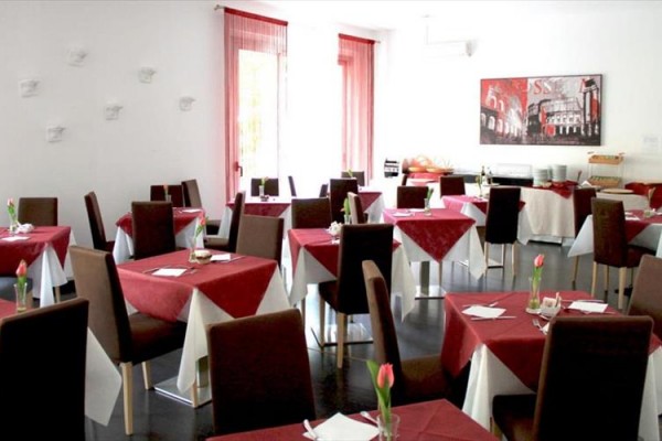 Restaurace s hnědými židlemi a stoly pokrytými červenobílými ubrusy.