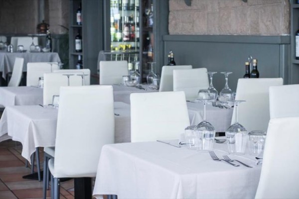 Restaurace s bílými židlemi a prostřenými stoly.