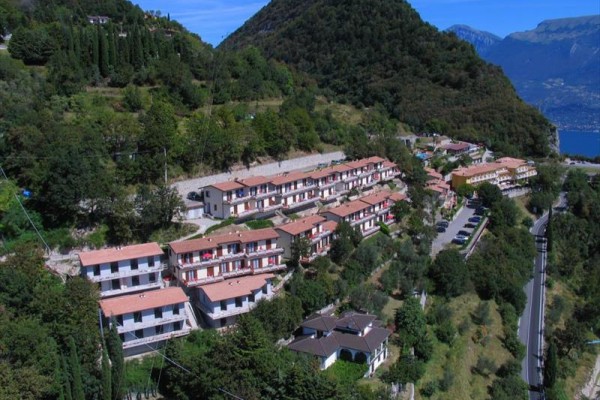 Řadové domy na svahu s výhledem na jezero a hory v pozadí.