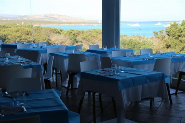Restaurace s modrými ubrusy a výhledem na moře.