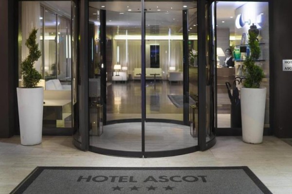 Vstup do hotelu s otočnými dveřmi a nápisem 