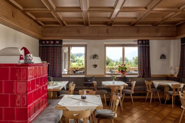 Tradiční interiér restaurace s dřevěným nábytkem a červenými kachlovými kamny.