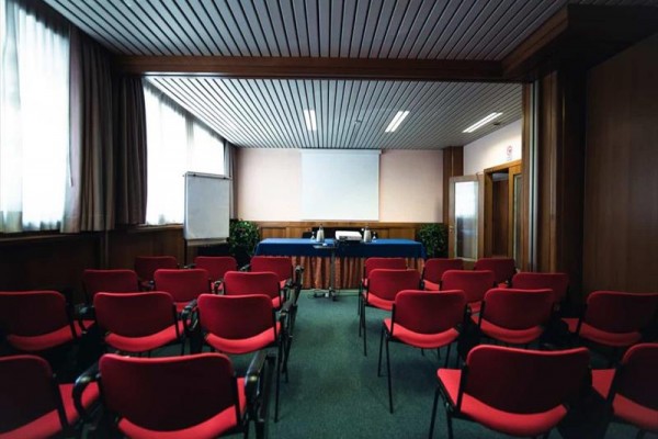 Konferenční místnost s červenými židlemi a projektorem.
