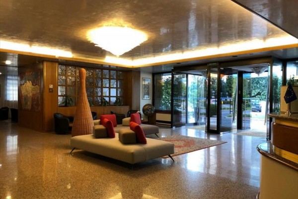 Elegantní hotelová lobby s pohodlnými pohovkami a skleněnými vstupními dveřmi.  