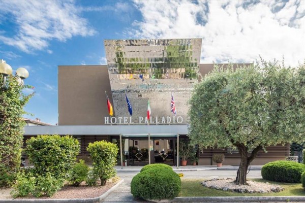 Vstup do hotelu s názvem Palladio s vlajkami na střeše.