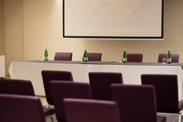 Konferenční místnost s prázdným stolkem a lahvemi vody.