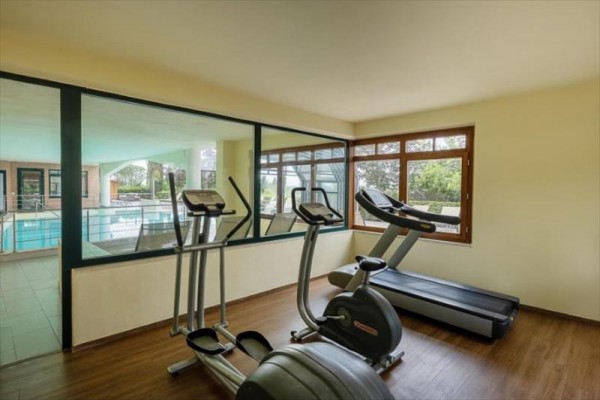 Místnost s fitness vybavením a výhledem na krytý bazén.