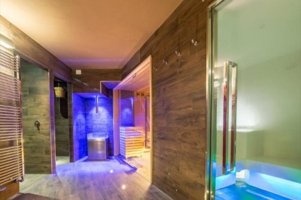 Moderní wellness s dřevěným obložením, saunou a barevným osvětlením.