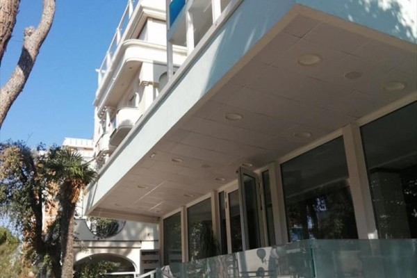 Moderní budova s prosklenou fasádou a balkony.