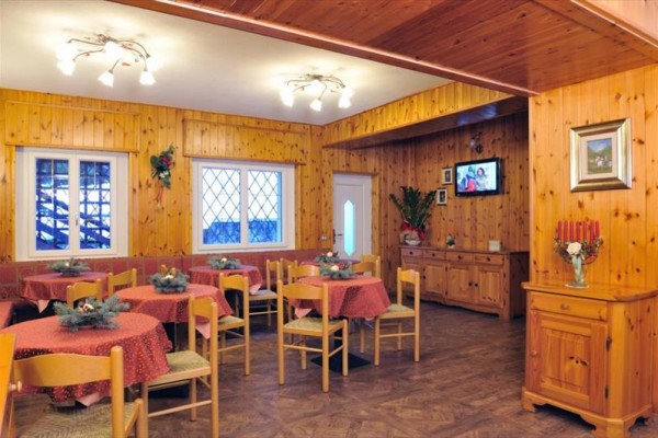 Restaurace s dřevěným obložením, červenými ubrusy a ozdobou na stolech.