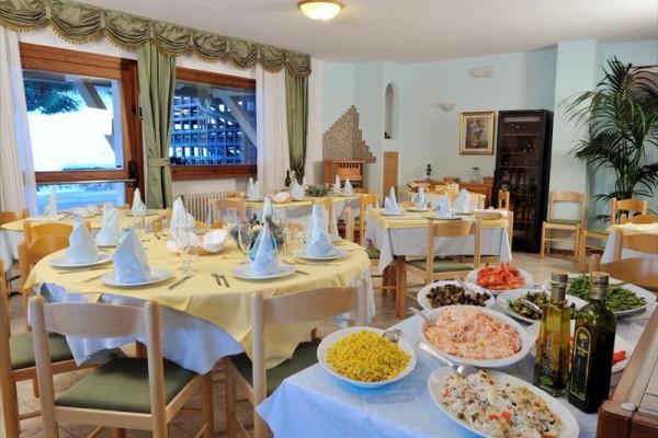 Restaurace s několika stolky připravenými pro hosty, na stole v popředí jsou různé saláty a olivové oleje.