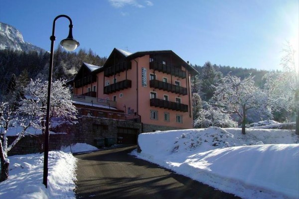 Hotel obklopený sněhem a zasněženými stromy při slunečném počasí.