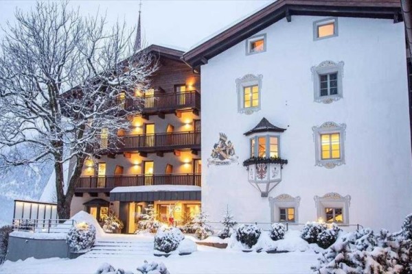 Zasněžený hotel s rozsvícenými okny a ozdobenou fasádou.
