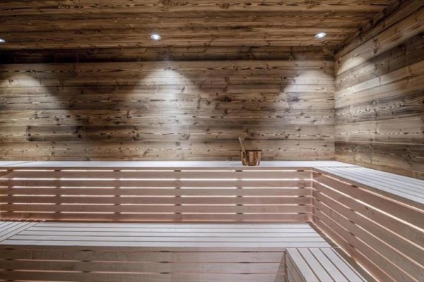 Dřevěná sauna s lavicemi a vědrem.
