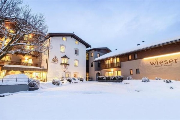 Zasněžený hotel Wieser s večerními světly a stromy.