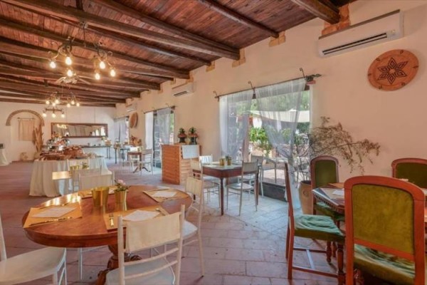 Interiér restaurace s dřevěným stropem, kulatými stoly a velkými okny.