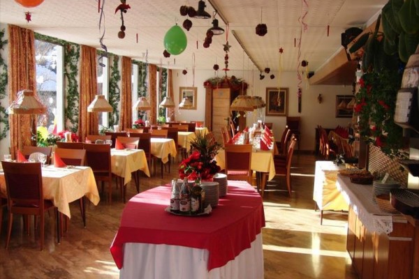 Svátečně vyzdobená restaurace s prostřenými stoly a svítícími dekoracemi.