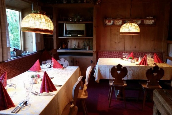 Uvnitř restaurace jsou dvě stoly s červenými ubrousky, ozdobené sklenicemi a příbory.