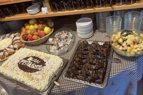 Dezertní bufet s dortem, ovocem a čokoládovými koláčky na oslavě Ferragosto.  