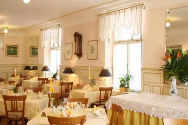 Stylová restaurace s prostřenými stoly a květinovou výzdobou.