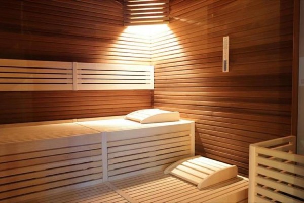 Dřevěná sauna s lavicí a polštáři osvětlená shora.