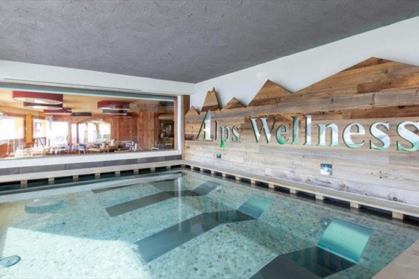 Vnitřní bazén s nápisem Alps Wellness na dřevěné zdi.