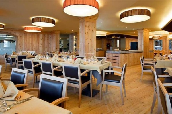 Prostorná restaurace s dřevěným interiérem a prostřenými stoly.