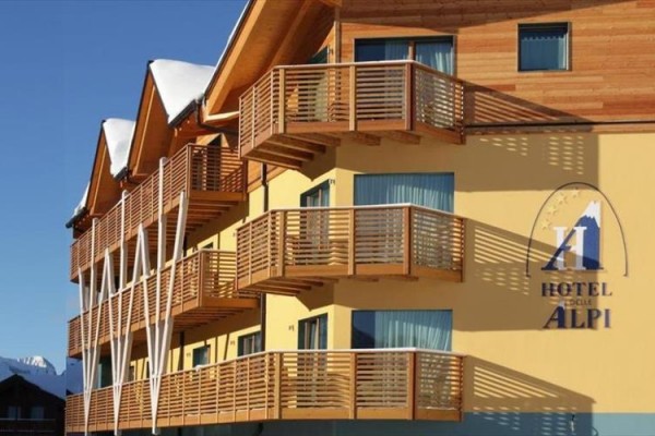 Moderní hotel se dřevěnými balkony ve slunečném počasí.