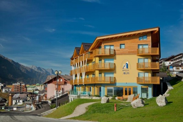 Dřevěný hotel ve svahu s výhledem na horskou vesnici a hory.