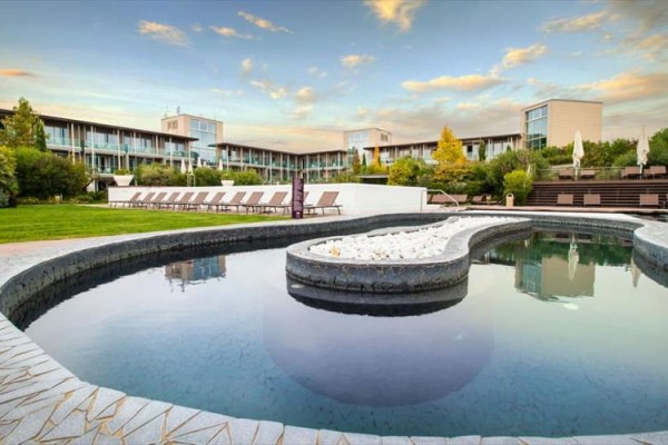 Moderní hotel s venkovním bazénem a lehátky na trávníku.