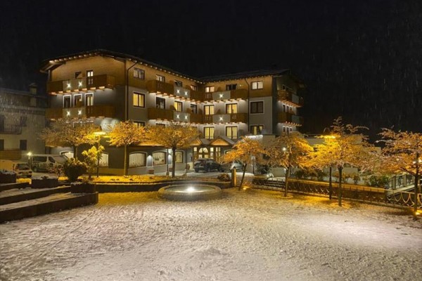 Noční pohled na osvětlenou budovu hotelu obklopenou zasněženou krajinou.