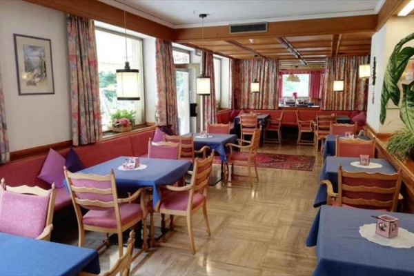 Restaurace s dřevěnými židlemi a modrými ubrusy.