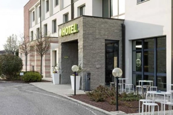 Vstupní část moderního hotelu s venkovním posezením.