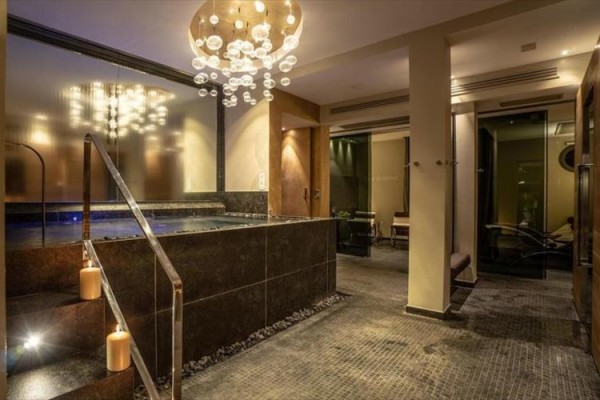 Luxusní wellness interiér se schodištěm do vířivky a moderním osvětlením.