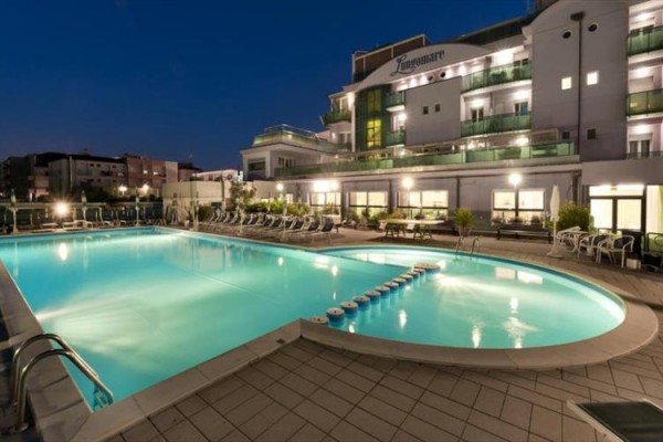 Noční pohled na osvětlený hotel s venkovním bazénem.