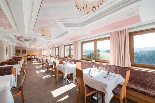 Světlá restaurace s prostřenými stoly, výhledem na krajinu a růžovým stropem.